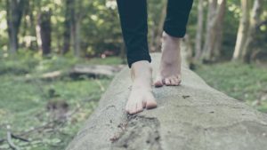 Barefoot adult walking on a log