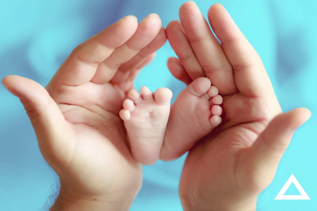Hands cradling a baby's feet.